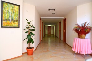 A hallway with a potted plant, a framed painting, and a table with a pink tablecloth.