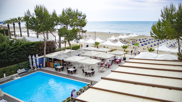 A poolside area with a swimming pool, umbrellas, and outdoor seating. - Hotel Oaz (Golem)