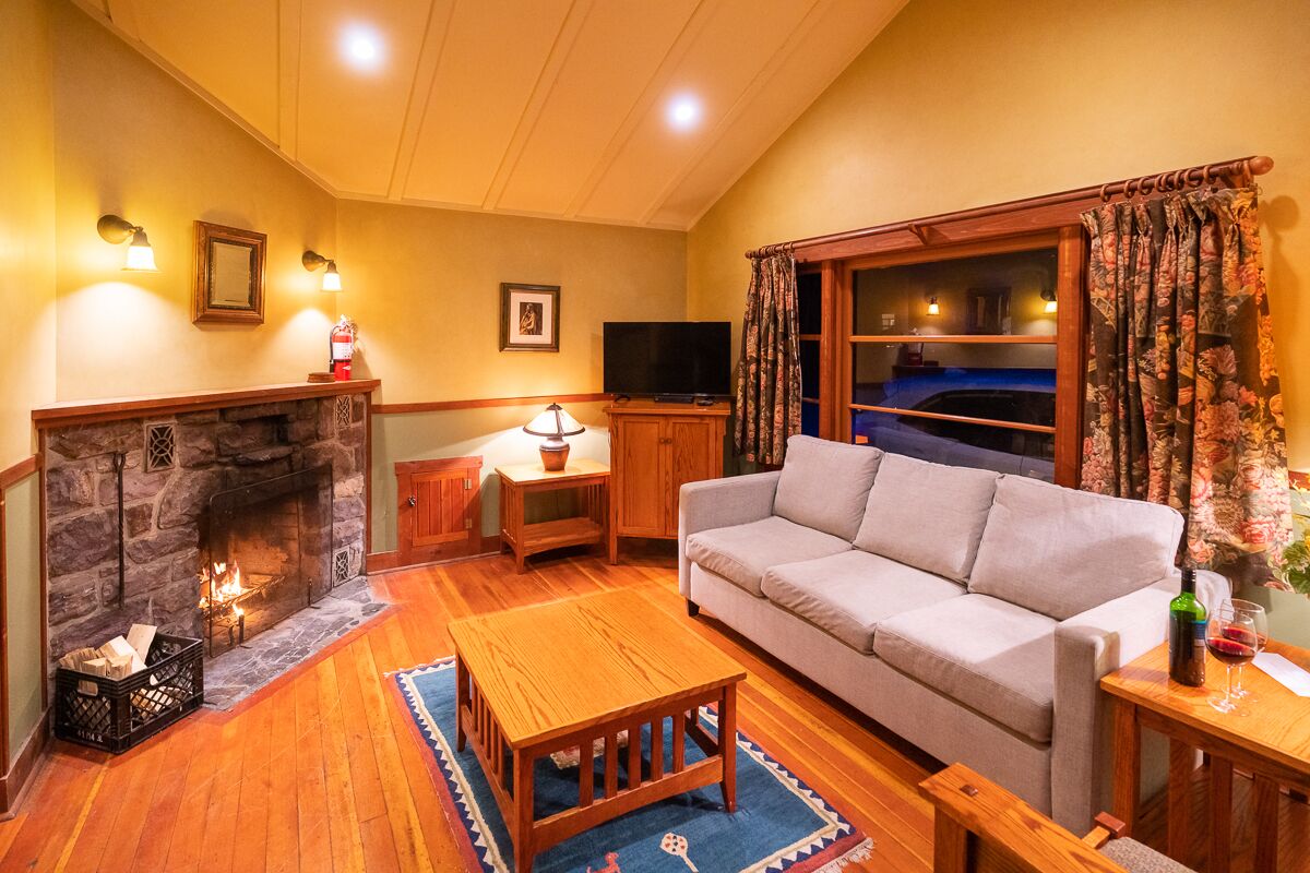 A cozy living room with a stone fireplace, a sofa, a wooden coffee table, and a television.