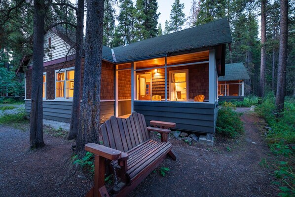A cabin with a wooden exterior, a bench, and a path leading to it.