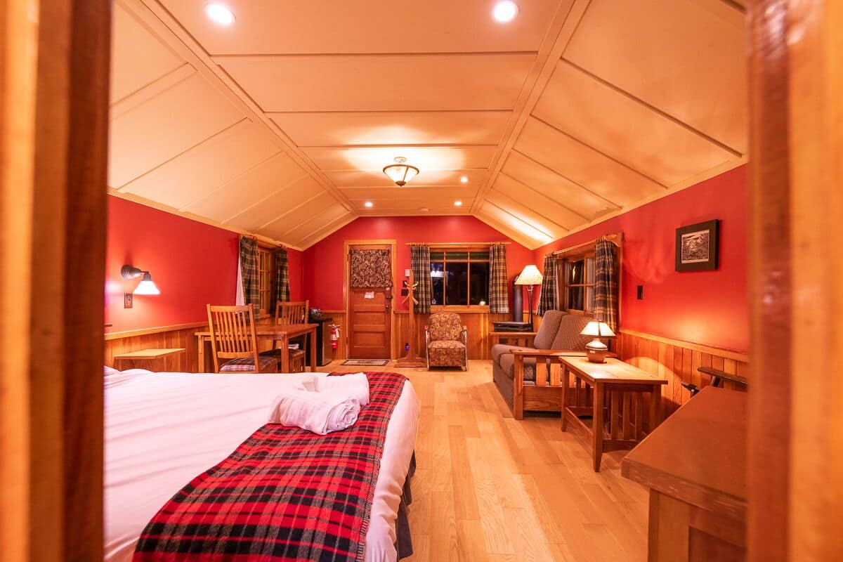 Een knus hotelkamer met een bed, een bureau en een stoel. Het heeft een houten plafond en een rode wand.