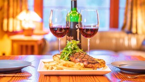 Een steak met frietjes en een fles wijn op een tafel.