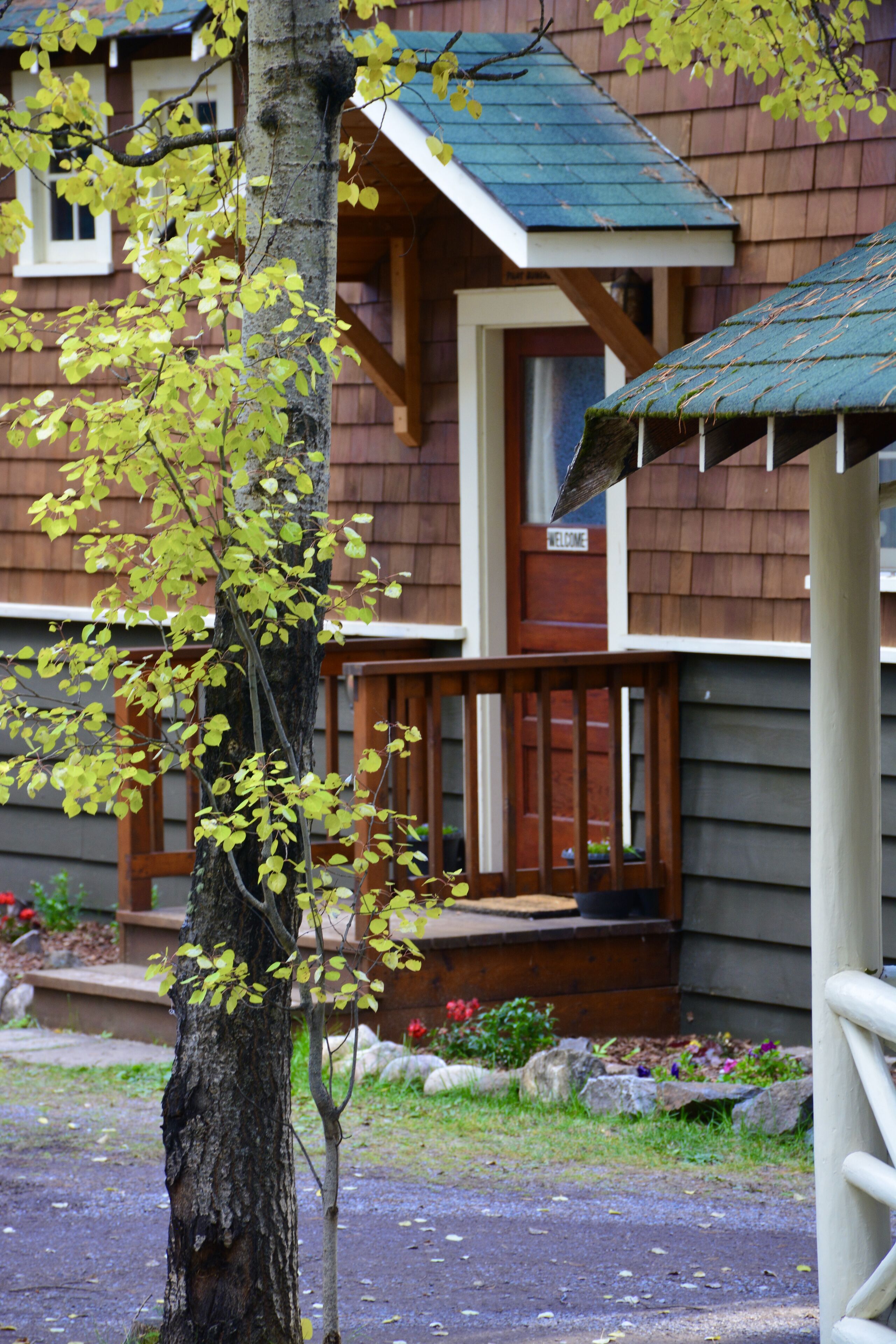 A wooden house with a porch, a door, and a window.