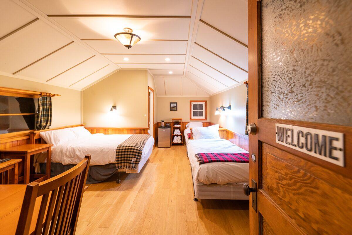Een gezellige kamer met twee bedden, een houten bureau en een 'WELCOME'-bord op de deur.