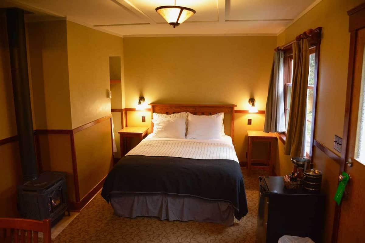 Een gezellige hotelkamer met een groot bed, twee nachtkastjes, een wandheater en een klein tafeltje met een waterkoker.