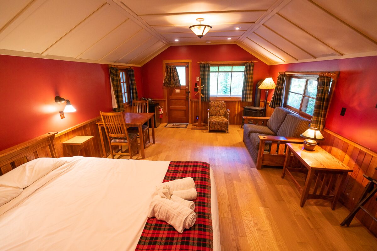 A cozy room with a bed, a chair, a sofa, and a small table.