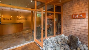 A reception area with a reception desk, a sign reading "SPA & RECEPTION", and a stone wall with a large rock. - Painted Boat Resort (Madeira Park)