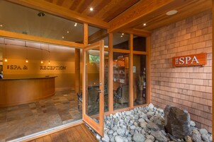 Un área de recepción con un mostrador, un letrero que dice "SPA & RECEPTION" y una pared de piedra con una roca grande.