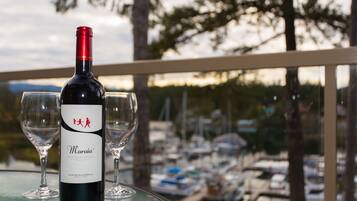 A bottle of wine and two glasses on a table with a view of a marina.