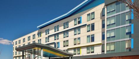 A modern hotel with a covered entrance, multiple floors, and a prominent 'WXYZ' sign.