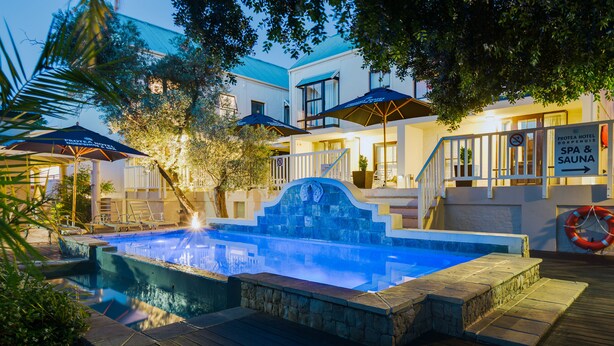 A pool area with a stone deck, umbrellas, and a sign for a spa and sauna. - Protea Hotel by Marriott Dorpshuis & Spa Stellenbosch (Stellenbosch)