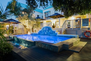 A pool area with a stone deck, umbrellas, and a sign for a spa and sauna.
