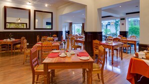 A spacious dining area with multiple wooden tables and chairs, large mirrors on the walls, and a chandelier. - Protea Hotel by Marriott Dorpshuis & Spa Stellenbosch (Stellenbosch)