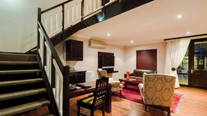 A staircase leading to a living area with a dining table, chairs, and a television. - Protea Hotel by Marriott Dorpshuis & Spa Stellenbosch (Stellenbosch)