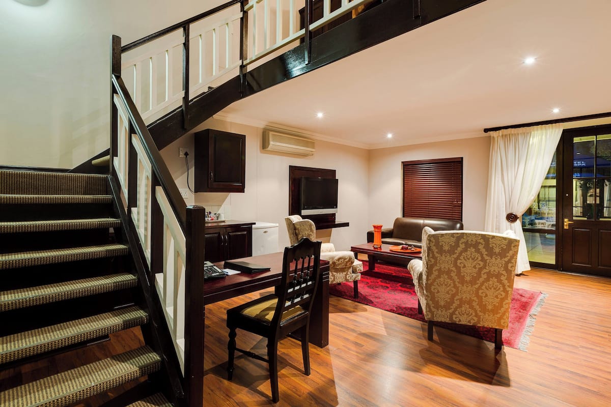 A staircase leading to a living area with a dining table, chairs, and a television.