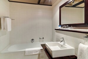A modern bathroom with a bathtub, a sink, and a large mirror. - Protea Hotel by Marriott Dorpshuis & Spa Stellenbosch (Stellenbosch)