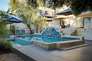 A hotel pool area with a stone-tiled pool, wooden deck, lounge chairs, and umbrellas. - Protea Hotel by Marriott Dorpshuis & Spa Stellenbosch (Stellenbosch)