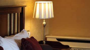 A hotel room with a bed, a nightstand, a lamp, and a wall with a patterned design.