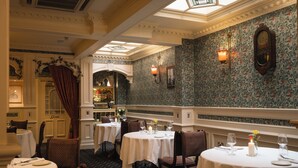 A dining area with round tables, chairs, and a chandelier. - Arbutus Hotel Killarney (Killarney)