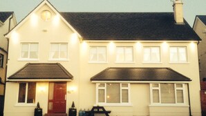 A two-story house with a red door, multiple windows, and a chimney. - Amber Hill Guesthouse (Galway)