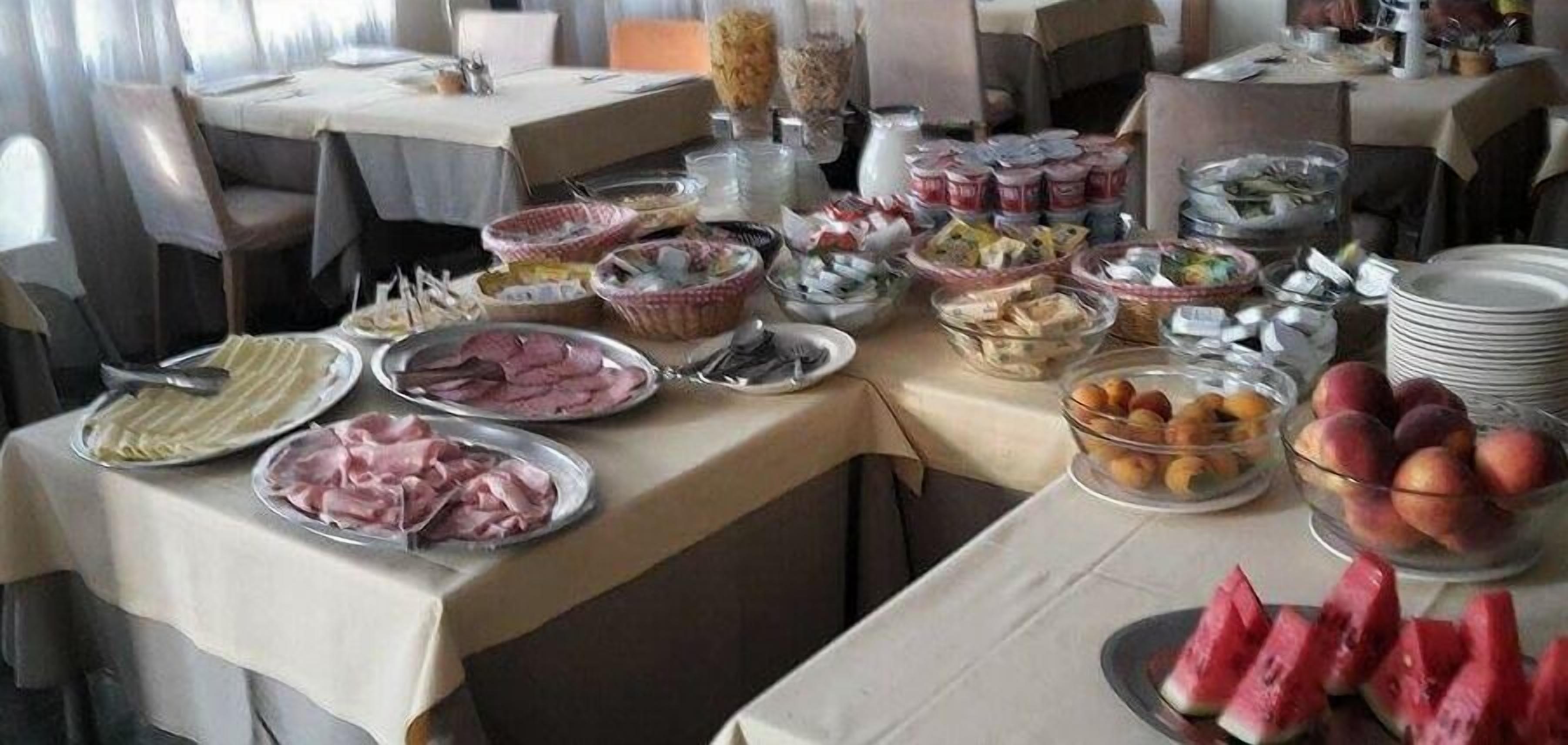 A buffet table with various food items including meats, cheeses, fruits, and desserts.