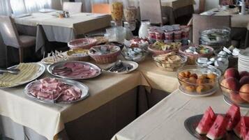 A buffet table with various food items including meats, cheeses, fruits, and desserts.
