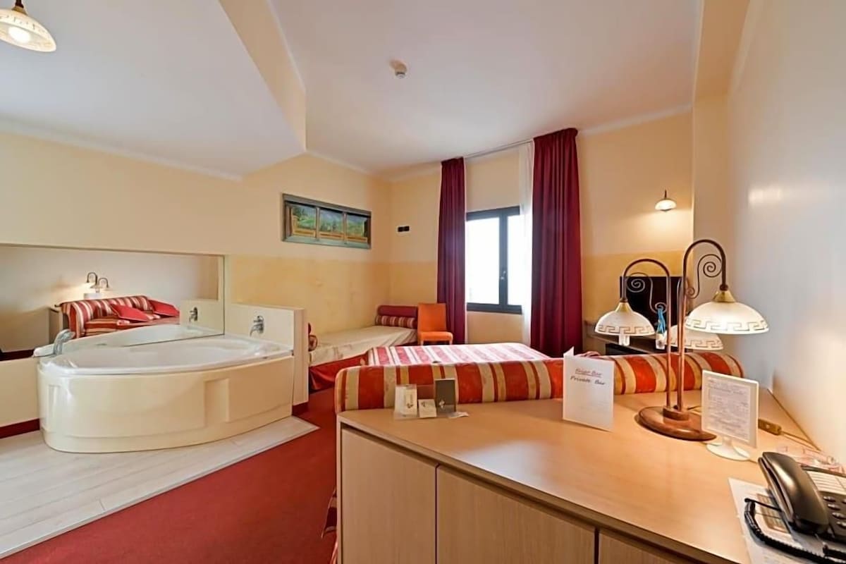 Une chambre d’hôtel équipée d’un lit, d’un bureau, d’un téléphone, d’une lampe et d’une baignoire.