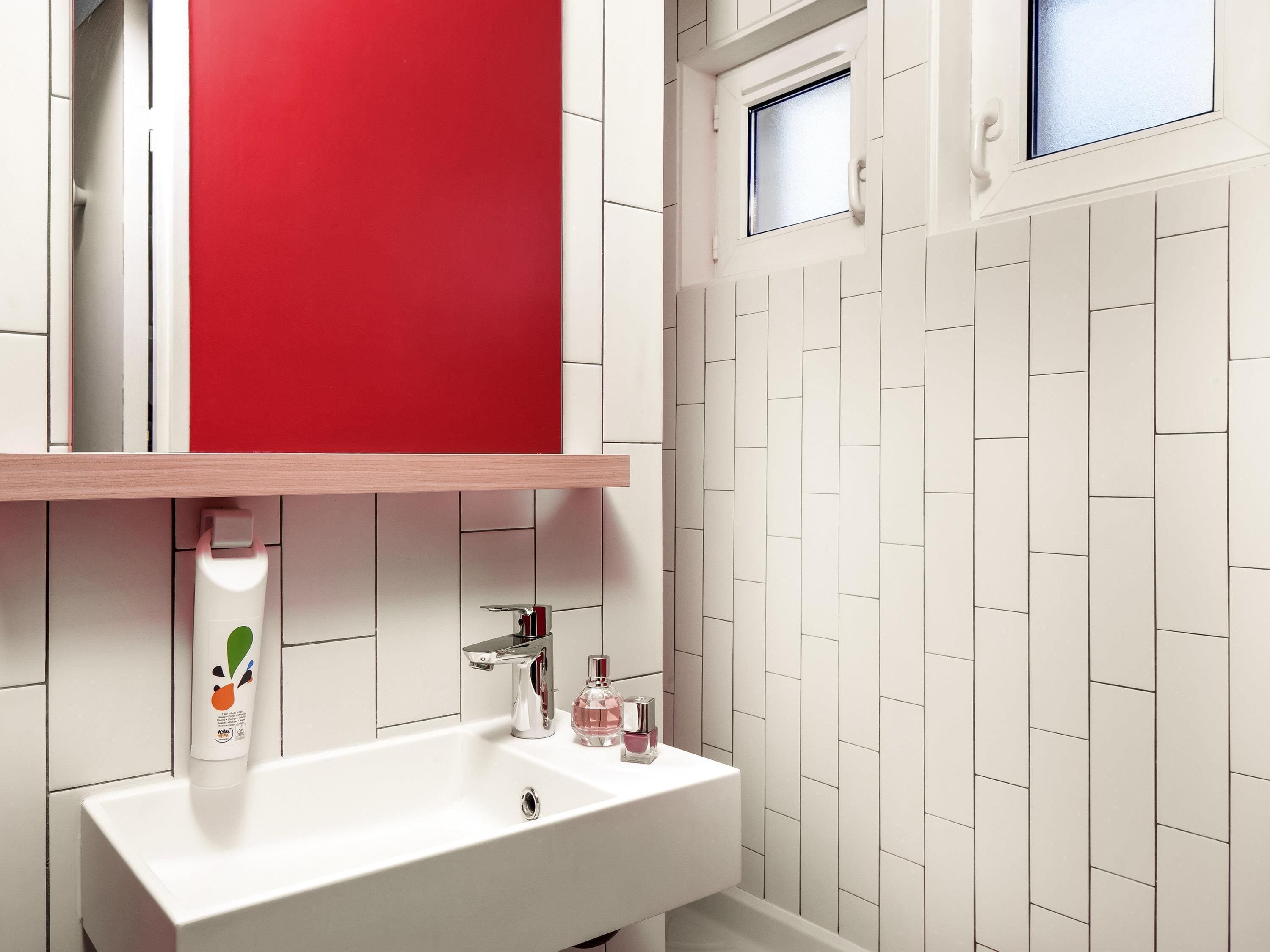 Ein Badezimmer mit einem weißen Waschbecken, einem roten Schrank und einem Fenster.