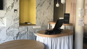 A modern hotel lobby with marble walls, a yellow archway, and round wooden tables with white curtains. - ibis Styles Vichy Centre (Vichy)