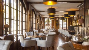 A spacious dining area with high ceilings, large windows, and modern chandeliers. - Hotel de la Poste - Relais Napoléon III (Bouillon)