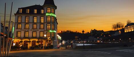A historic building with multiple stories, featuring a prominent corner tower and a ground-level bar.