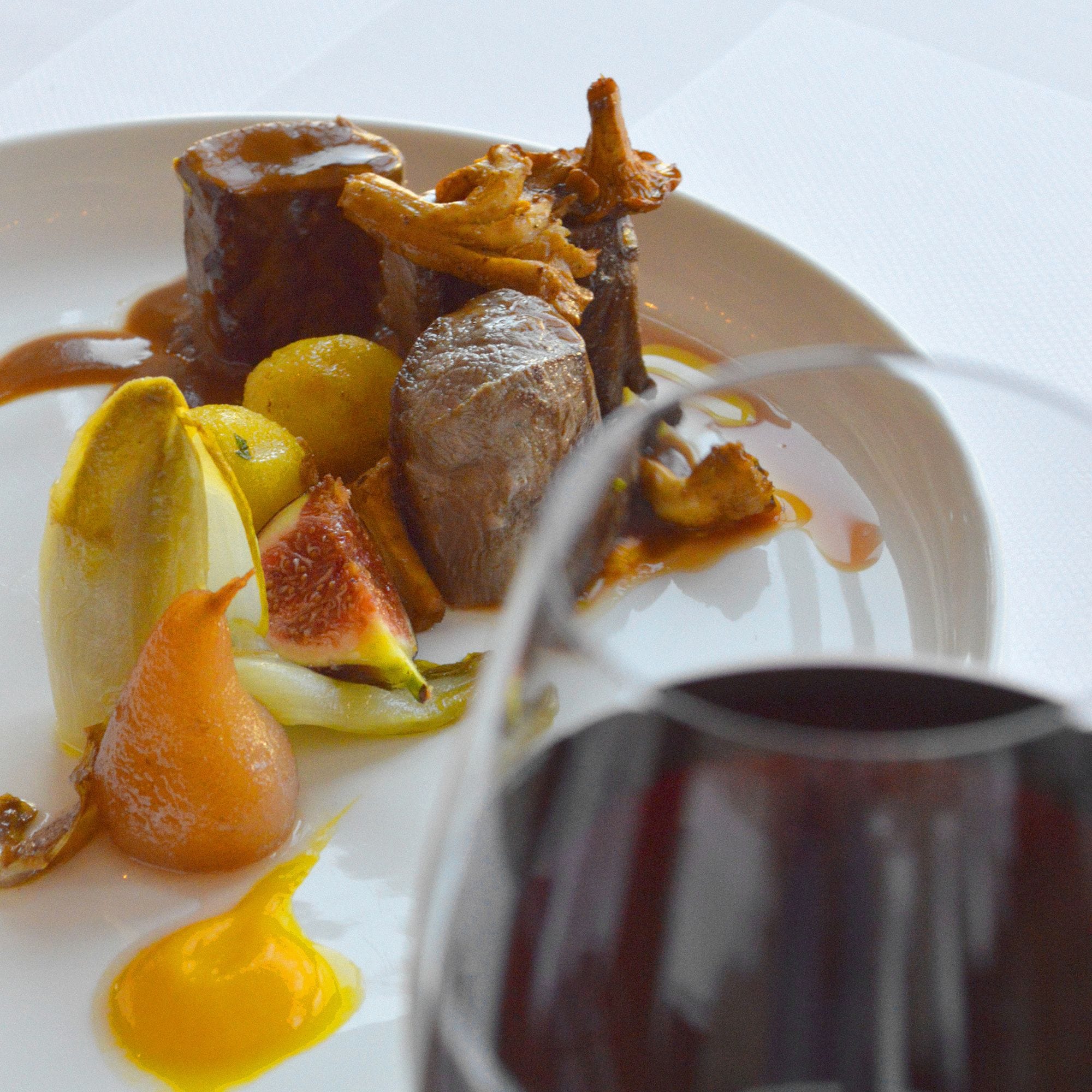 A plate of food with a glass of red wine.