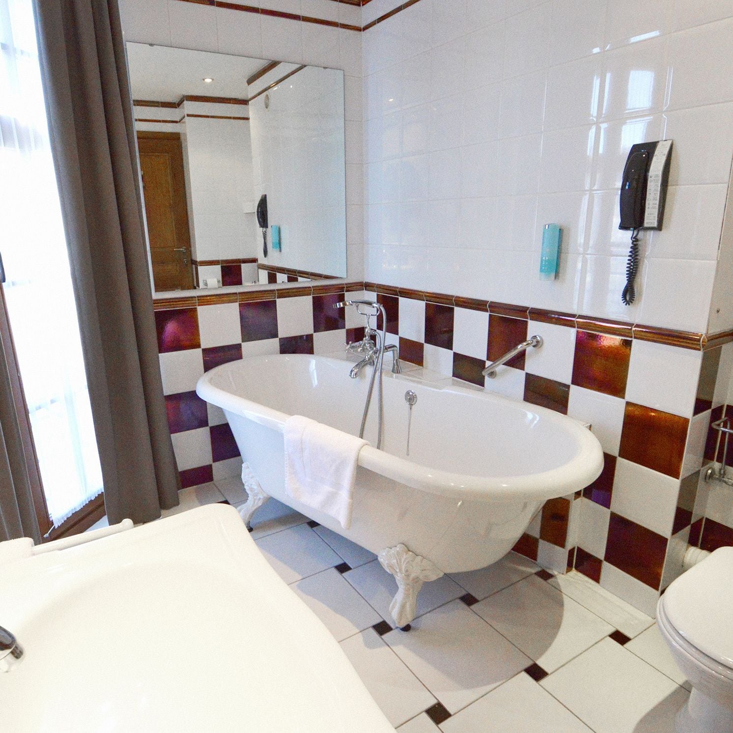 Een badkamer met een vrijstaand bad, een toilet en een wastafel.