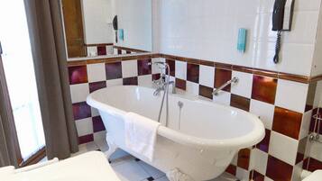 Een badkamer met een vrijstaand bad, een toilet en een wastafel.