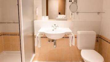 Un baño con ducha, lavamanos, inodoro y espejo.