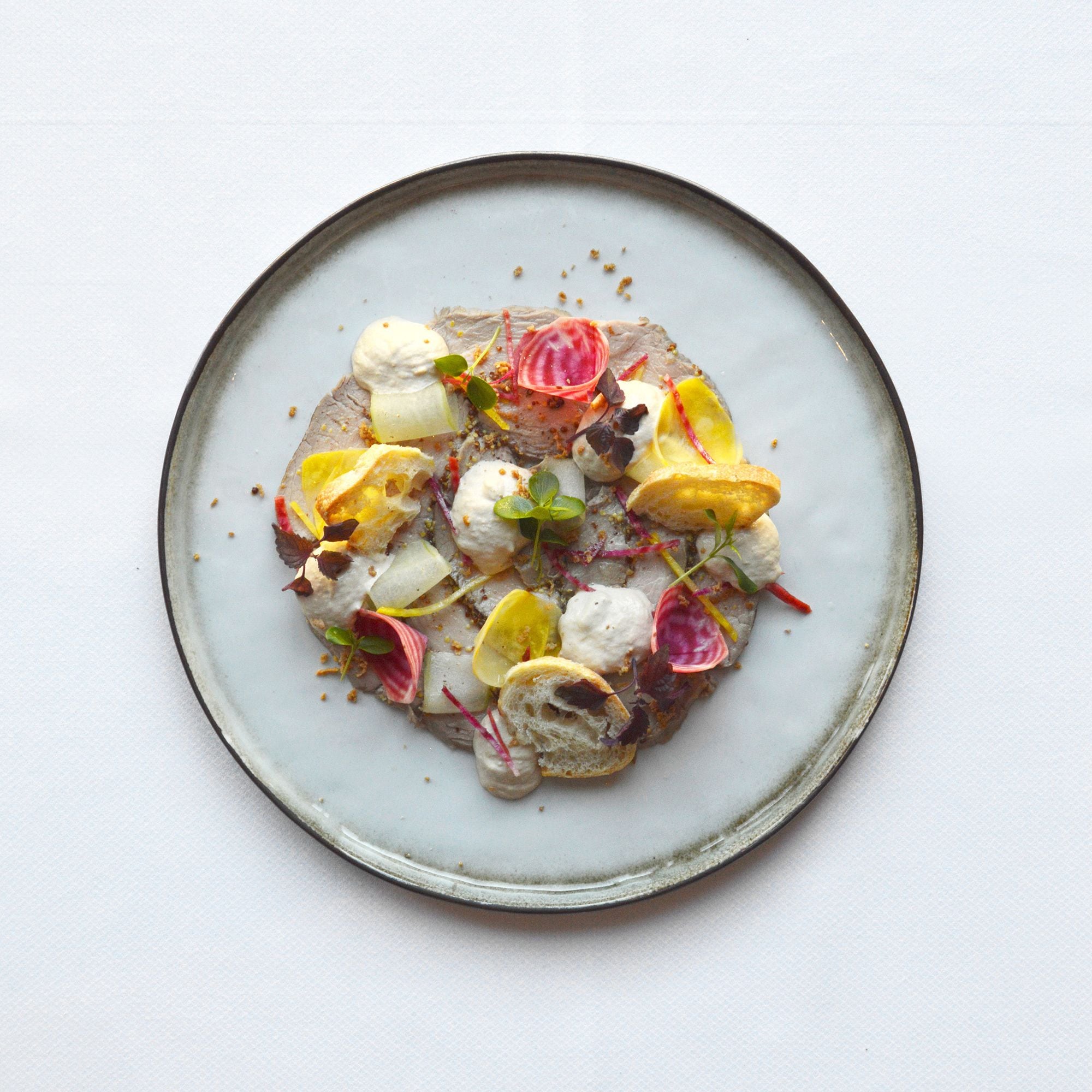 Une assiette contenant une variété d’aliments, notamment un morceau de viande, des légumes et des accompagnements.