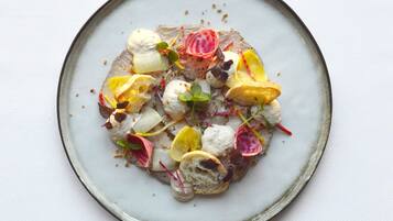 A plate with a variety of food items including a piece of meat, vegetables, and garnishes.