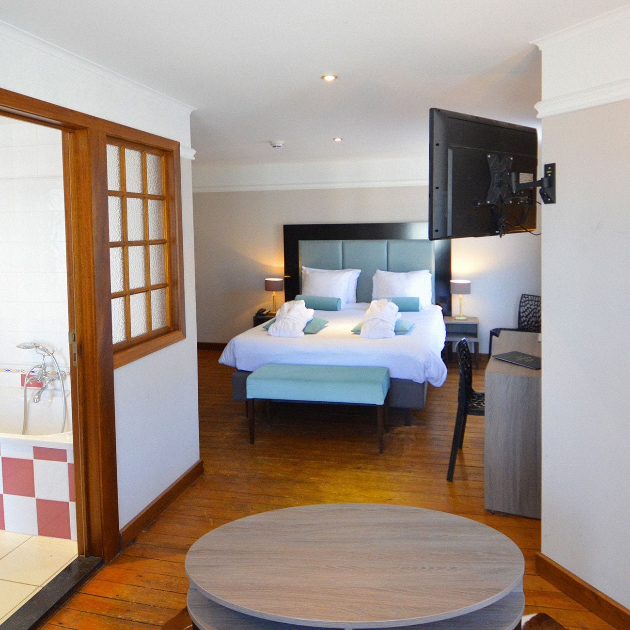Une chambre d’hôtel avec un grand lit, des tables de chevet, une table ronde et une vue sur l’extérieur.