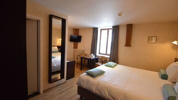 Una habitación de hotel con una cama grande, un escritorio, una silla, un televisor y una ventana con cortinas.