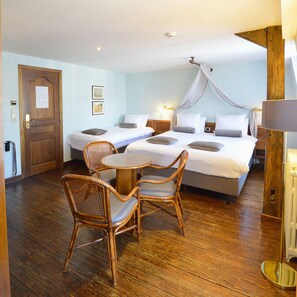 A hotel room with a large bed, two smaller beds, a dining table, wicker chairs, and a canopy bed. - Hotel de la Poste - Relais Napoléon III (Bouillon)