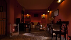 Una habitación tenuemente iluminada con una pared roja, un sofá blanco, una mesa de madera y una cesta de mimbre.