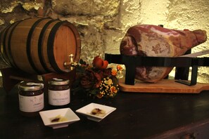A wooden barrel, two jars of gelatina, a large piece of meat on a wooden board, and a small plate with food remnants. - Cortile di Venere Bed & Breakfast (Trapani)