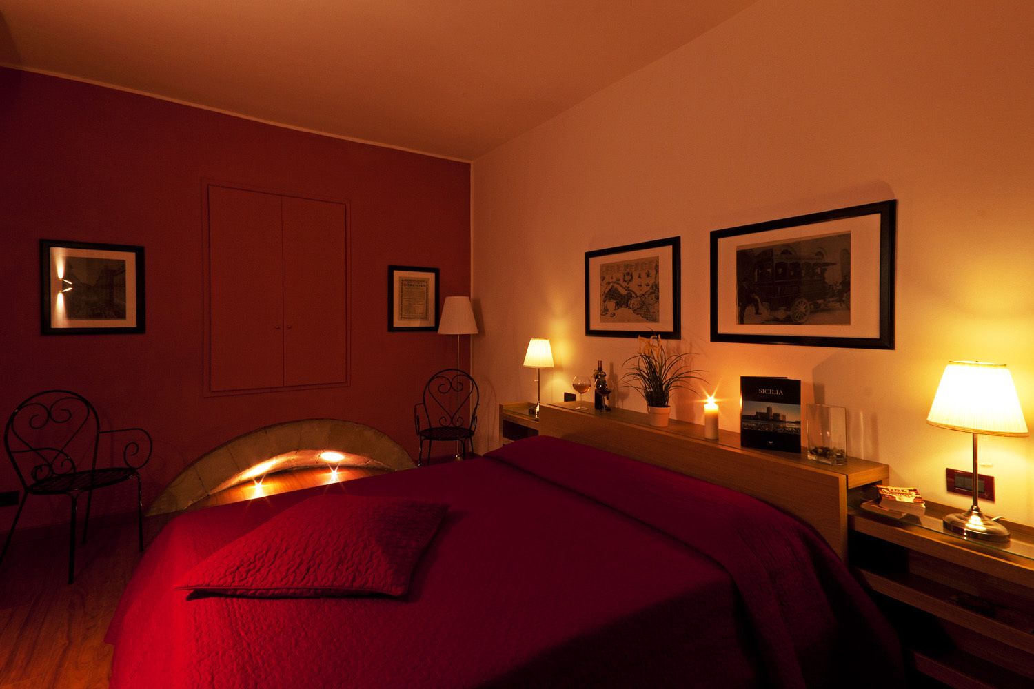 A hotel room with a bed, a desk, a chair, and a fireplace.