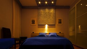 Un dormitorio con una cama grande, una mesita de noche, una silla y un armario.