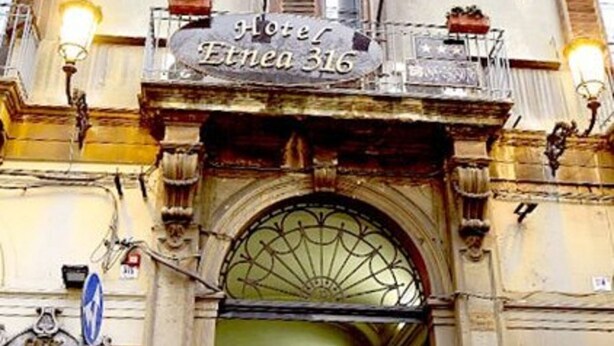 L’entrée d’un bâtiment historique, sur laquelle on peut lire l’inscription « Hôtel Etnea 316 ».