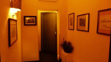 A hallway with a door marked '7', framed pictures on the walls, and a potted plant.