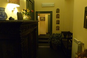A dimly lit hallway with a lamp, a vase with flowers, and a radiator.