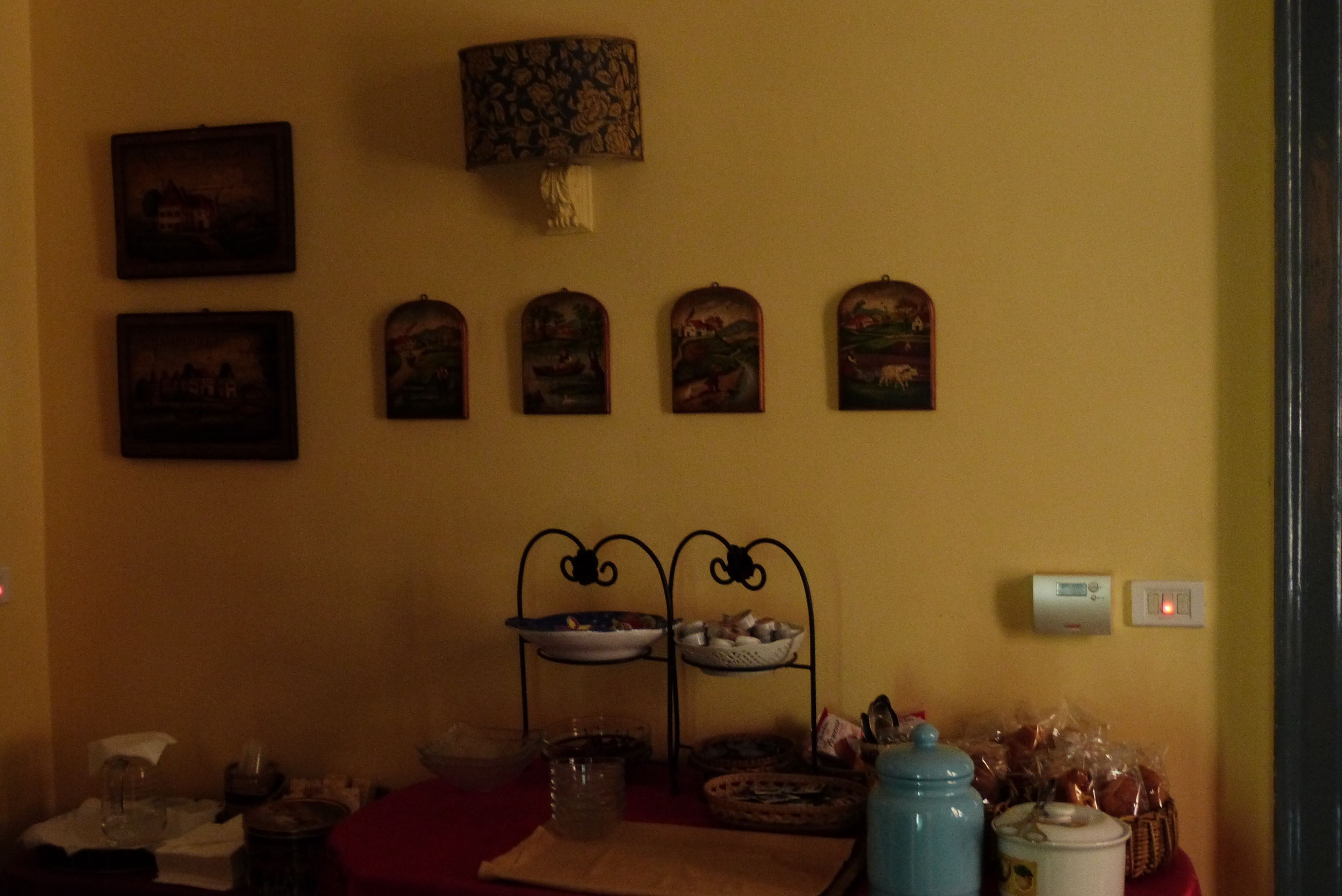 Un comedor con una mesa lista para dos, una lámpara de pared y varias fotografías enmarcadas.