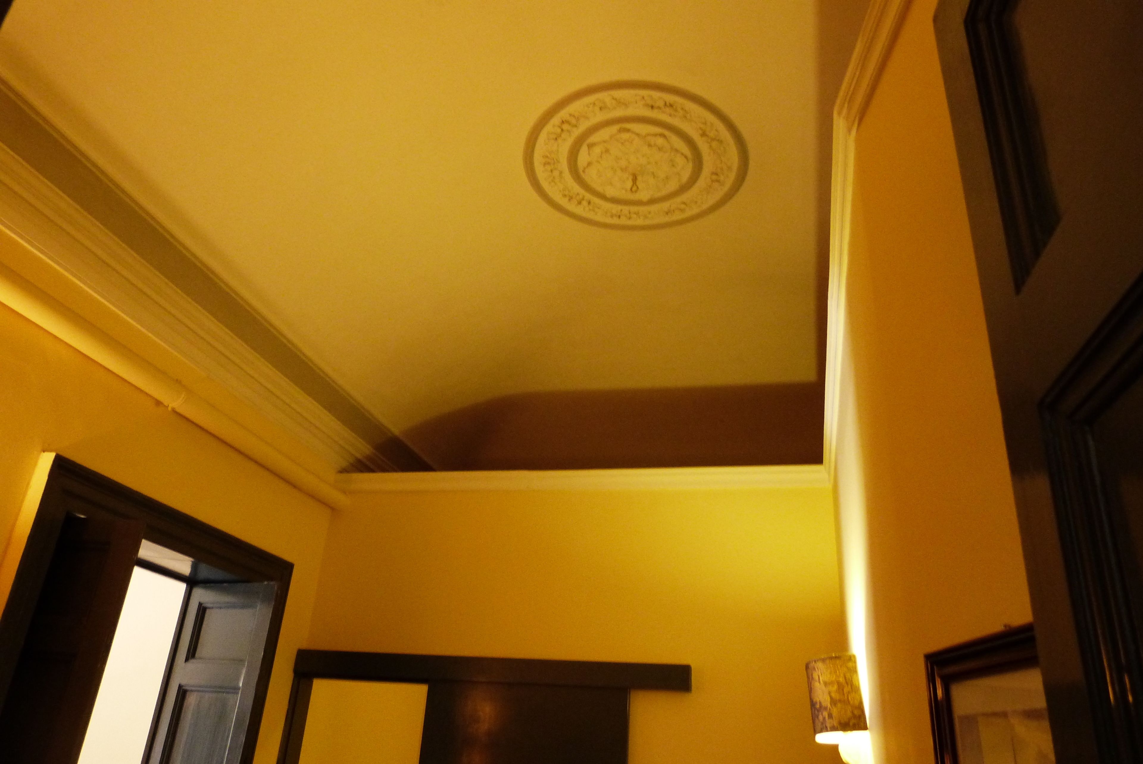 Um quarto com teto alto, uma moldura decorativa no teto e uma porta que dá para outro cômodo.
