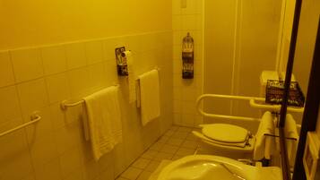 A small bathroom with a toilet, a bathtub, and a sink. There are two towels hanging on the wall.